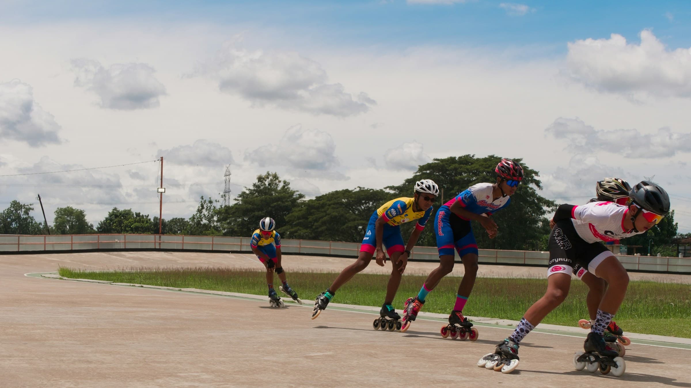 Junior inline speed skaters racing around the bend of an outdoor track