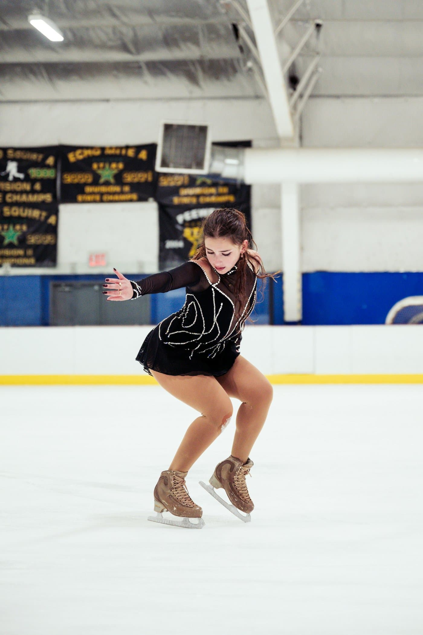 A young figure skater gliding across an indoor ice rink