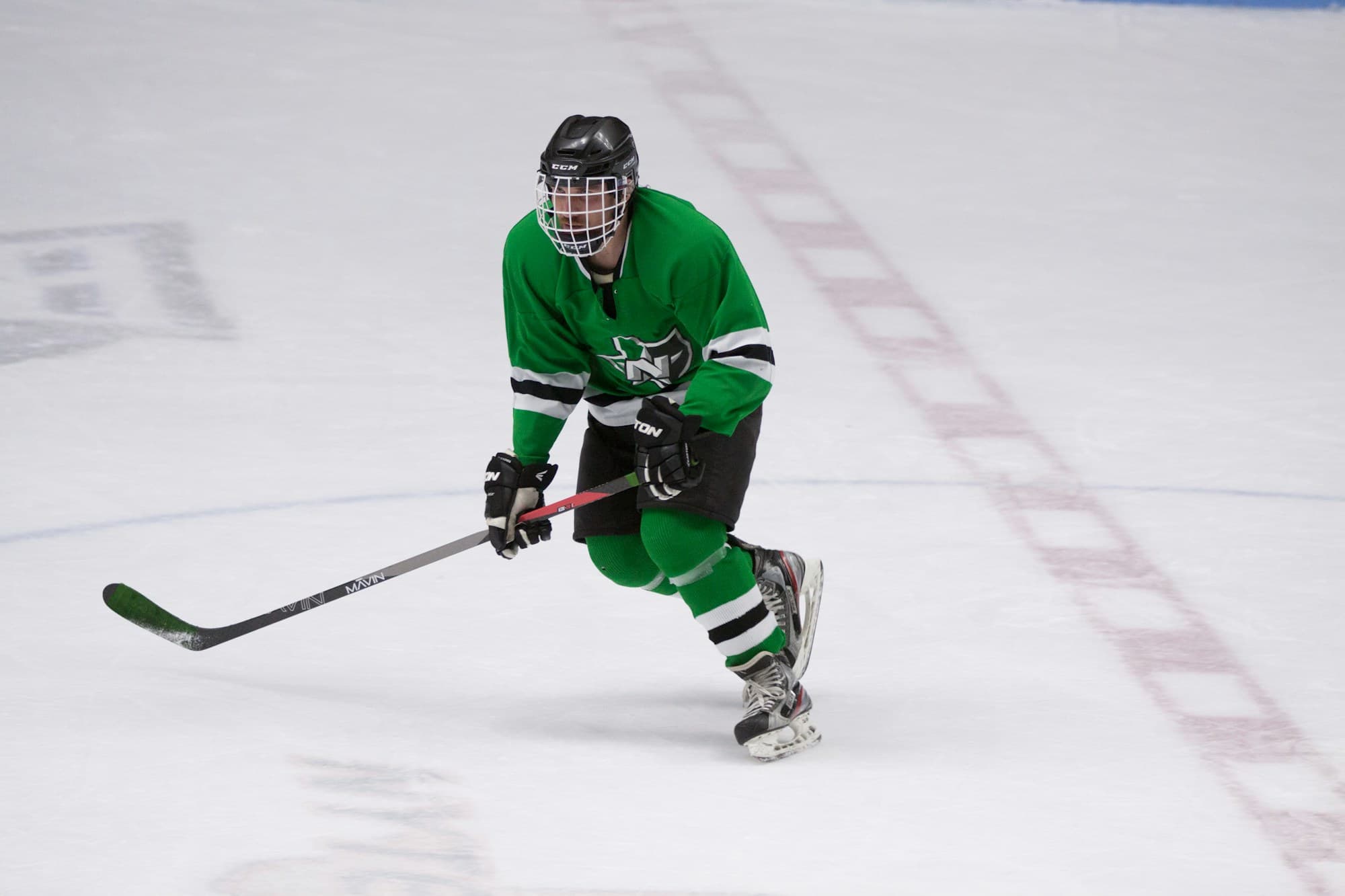Hockey player in full gear driving forward with stick on the ice