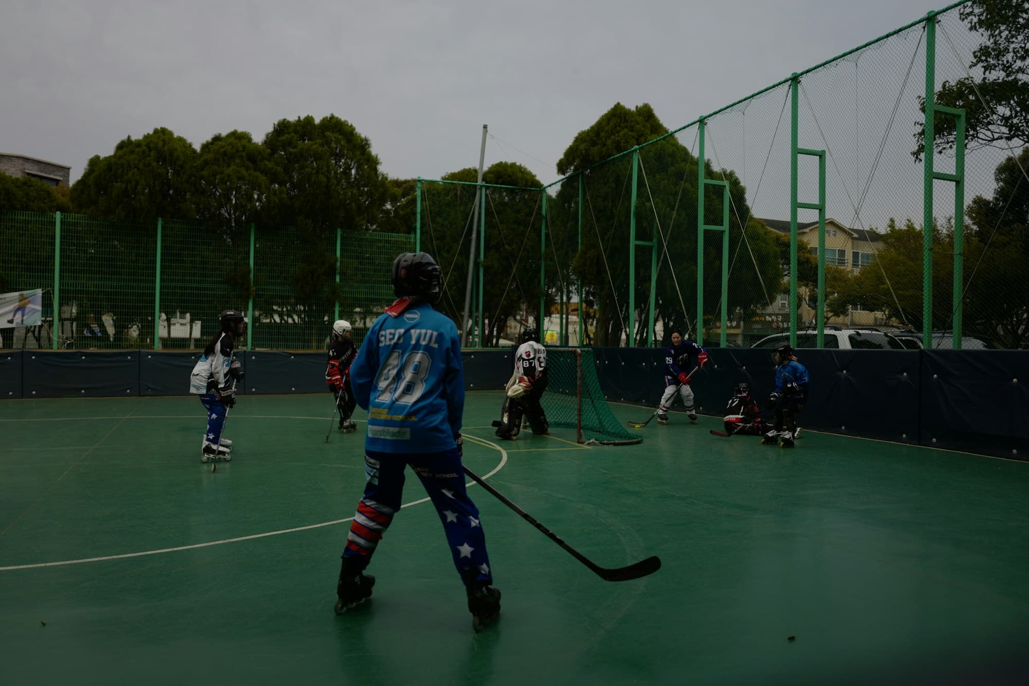 Players in a roller hockey match on an outdoor court